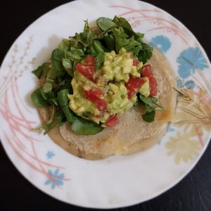 Pancake with guacamole and arugula salad with tomatoes