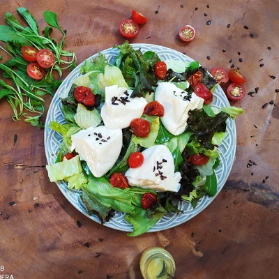Recipe of Burrata salad with mixed leaves in dijon sauce topped with cocoa nibs on the DeliRec recipe website